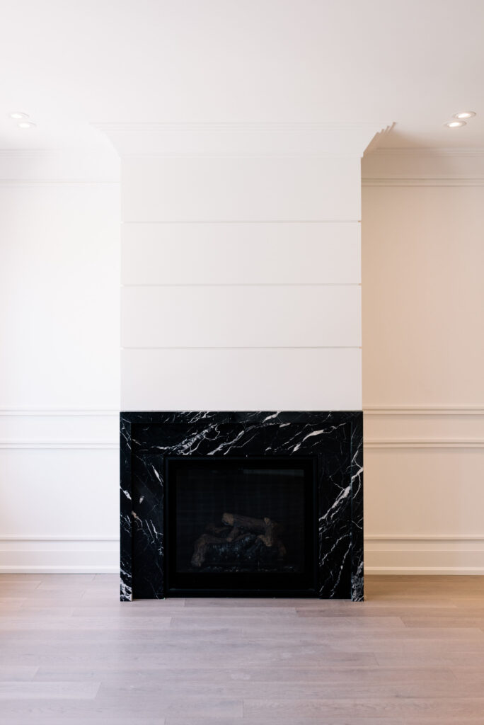 Modern black marble fireplace with oak hardwood flooring, designed by Qarnis Development in Toronto.