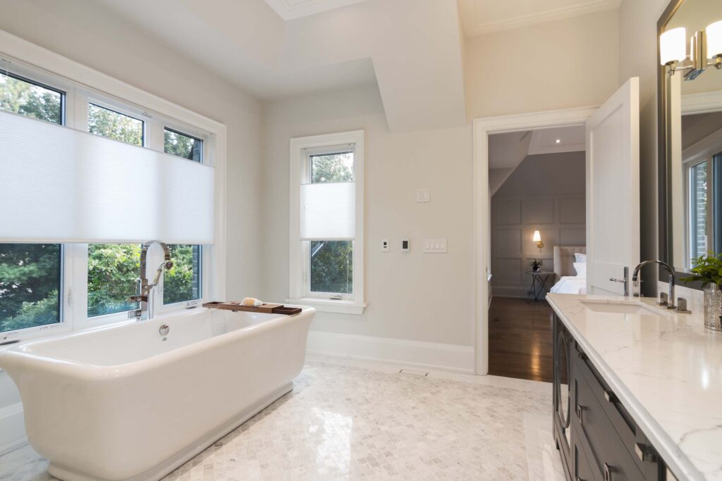 Luxury marble bathroom in Toronto with freestanding bathtub, custom vanity, and mosaic flooring by Qarnis Development.